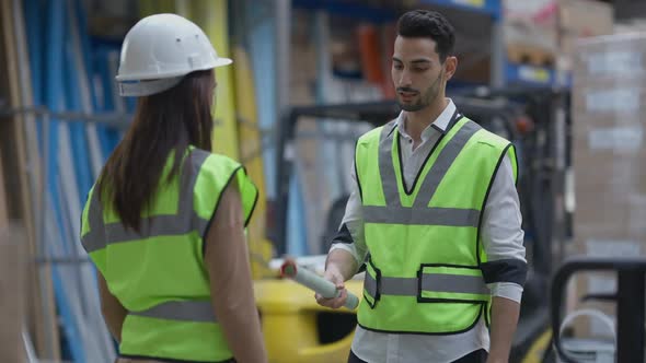 Confident Middle Eastern Man Passing Blueprint to Caucasian Woman Shaking Hands with Colleague alt