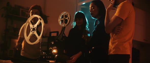 Young woman introduces vintage projector for friends on movie night alt