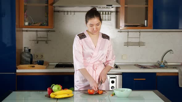 Girl Makes Salad Standing at Table and Cutting Vegetables alt