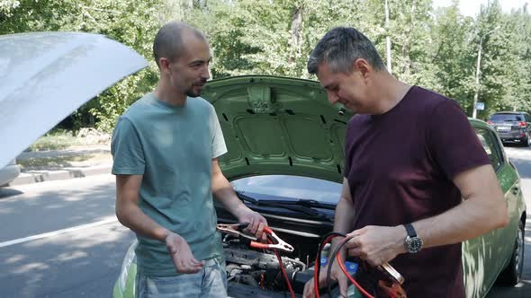 Two Men Helping to Charge a Car Battery