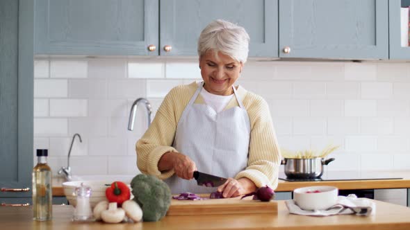 Happy Woman with Knife Chopping Onion on Kitchen