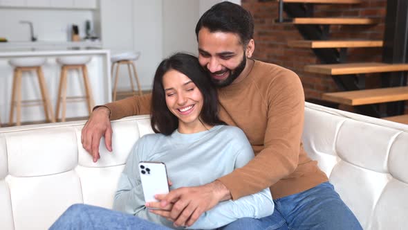 Positive Indian Couple in Love Spends Time Together at Home Using Smartphone