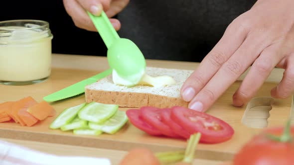 Woman's hands spreading salad cream on whole wheat bread for making healthy sandwich