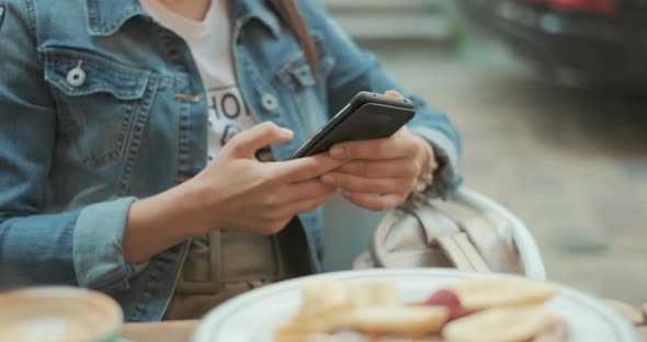 Hands of Young Woman Are Using Smartphone During Coffee Break in Cafe alt