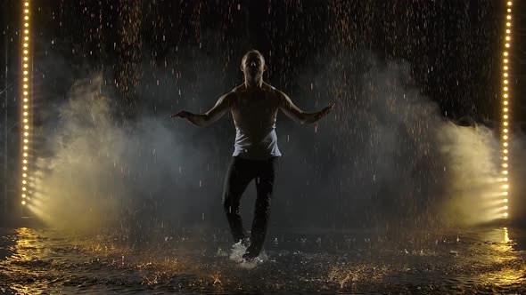 Male Dancer Dancing Elements of Salsa in the Pouring Rain. Silhouettes of a Man in Wet Clothes alt