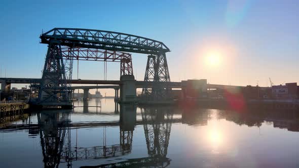 Low level aerial push in shot of ferry bridge Nicolas Avellaneda over the Matanza River during sunri alt