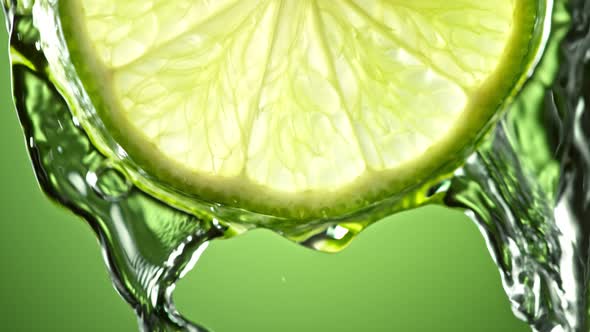 Super Slow Motion Macro Shot of Flowing Water From Lime Slice on Green Background at 1000Fps alt