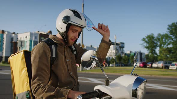 A Delivery Man on a Scooter Parks Along the Road to Look at the Correct Address