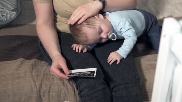 A beautiful woman wife holds an ultrasound image of a baby in her hand. alt