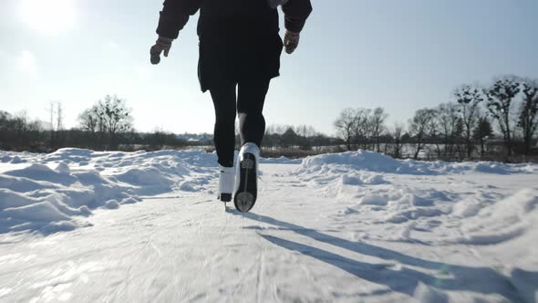 Professional female skater in white figure skates is skating on frozen lake alt