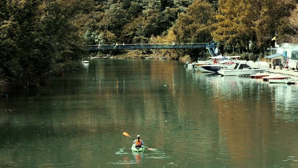 A young woman in life jacket is rowing a kayak on the river. Back view. Real time. alt