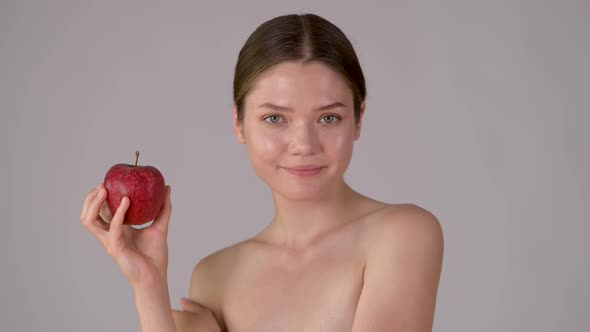 Beautiful girl holding apple smiling and enjoying natural skin care alt