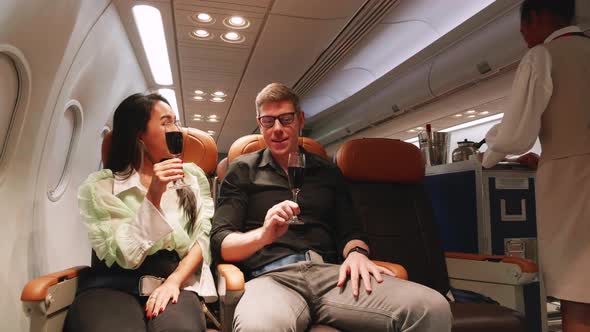 young couple cheers the champagne glasses while traveling on airplane