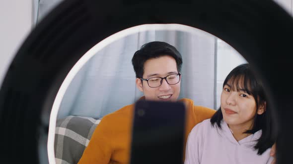 Young Asian Couple Influencers Streaming Video on Social Media Using Smartphone alt