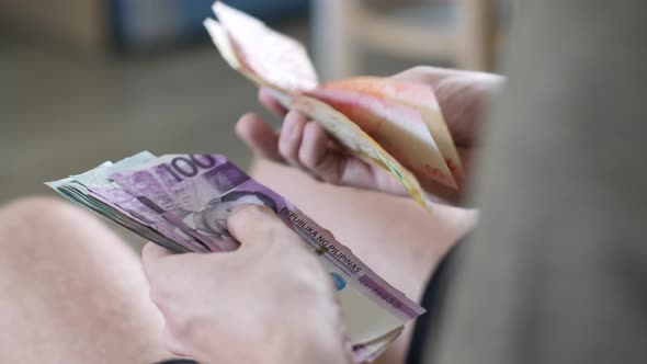 Men's Hands Count Cash Philippine Pesos and Other Currencies at Home in a Bright Room alt