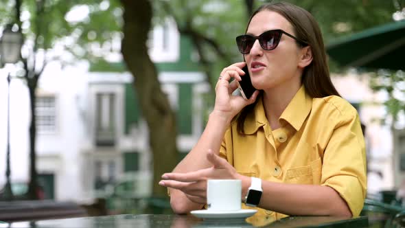Happy Cheerful Woman Talking on Smartphone Sitting in the Park