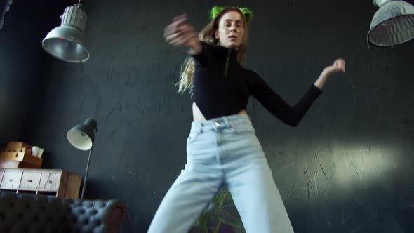 Girl with Bright Green Hair is Dancing in a Hall with Black Walls and Floor alt