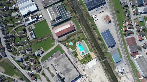 Top down aerial view over a swiss city with a river and an outdoor pool. alt