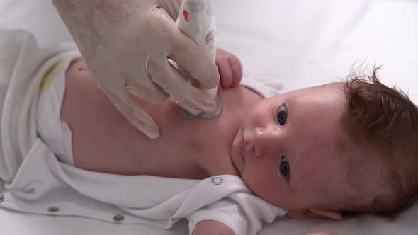A Female Doctor Conducts an Ultrasound Examination of Soft Tissues and Internal Organs of a Newborn