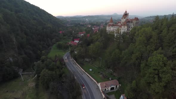 Aerial of Bran Castle on a hill near a village alt