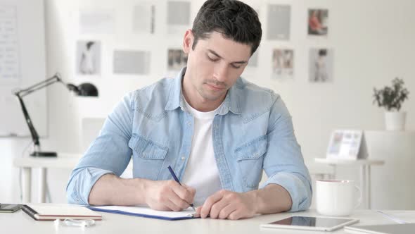 Casual Young Man Writing in Office alt