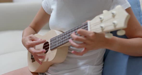 Woman play with ukulele at home alt