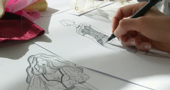 The designer draws with a pencil a sketch of fashionable women's clothing on paper. 
