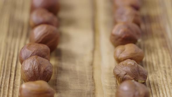Sliding Shot of Dried Hazelnuts Lying in Row on Textured Wooden Table Surface alt