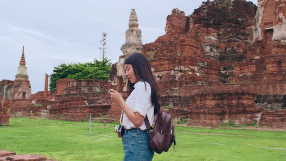 Asian backpacker blogger woman casual with camera look at photo on smartphone.