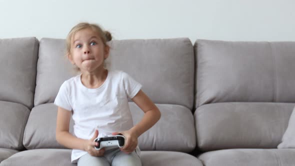 Cute Little Girl at Home Playing with a Controller Joysticks in Front of a Computer Screen