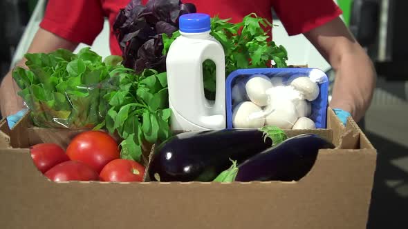 Closeup View of Man Courier Posing with Box of Organic Food in Hands During Working Day Spbd alt