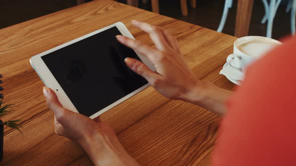 Woman using digital tablet while having coffee alt