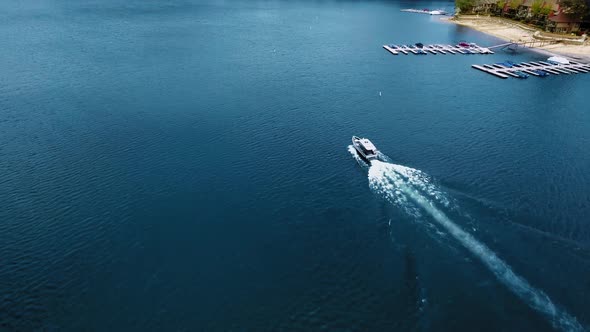 A drone flies over the boat sailing in the lake, aerial view of Lake Arrowhead, California, USA alt