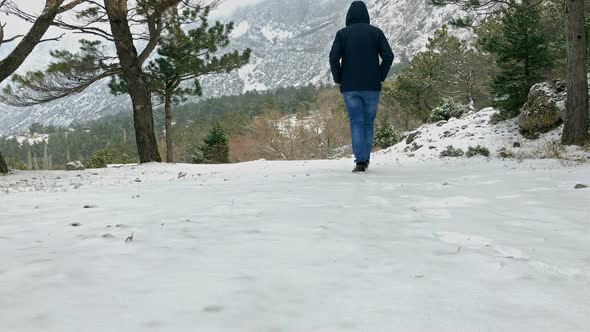 Man in Jeans and Jacket Walking on Snow on Mountain