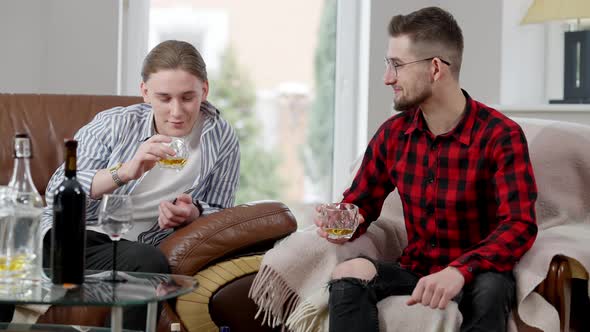 Portrait of Joyful Young Man Talking with Friend Holding Glass with Scotch alt