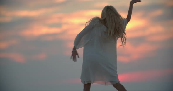 Sexy Woman in White Dress is Dancing Colorful Sunset Sky in the Background alt