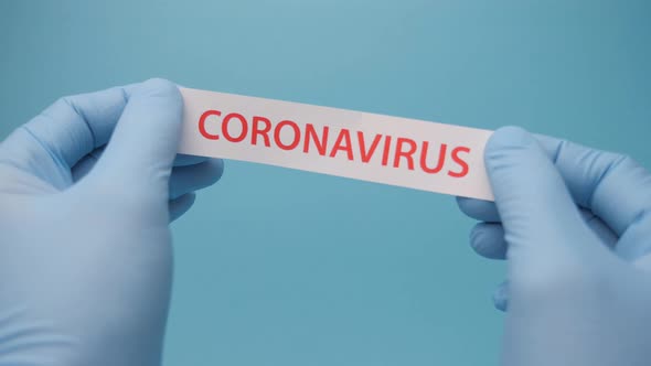 Found Vaccine. Hands Researcher in Gloves Tearing a Piece of Paper with Coronavirus Print on It alt