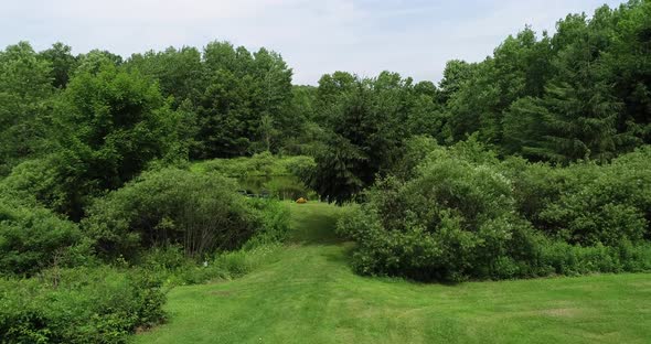 A drone rises over a well kept property to reveal a small private bass pond. alt