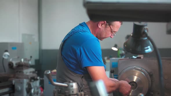 The Turner Processes the Metal Part on a Lathe in a Lathe Shop alt