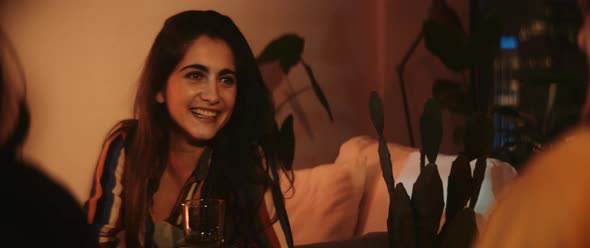 Young woman with drink in her hand interacts and laughs alt