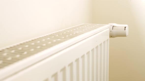 Person's Hand Adjusting Temperature On Thermostat To Control Heat In Central Home Heating System alt