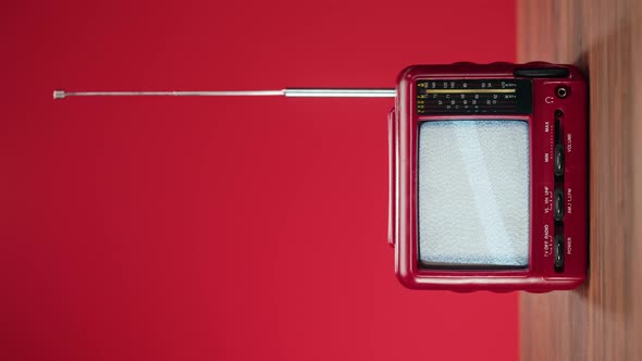 Vertical Video of Turning Off Small Old Television with Grey Interference Screen on Red Background alt