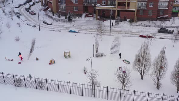 Children Go Sledding and Tubing From the Slide After a Snowfall in the Courtyard of an Apartment