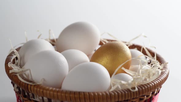 Close-up of a basket with white and golden chicken eggs. alt
