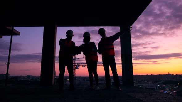 Builders Work with a Blueprint, Standing in Unfinished Building alt
