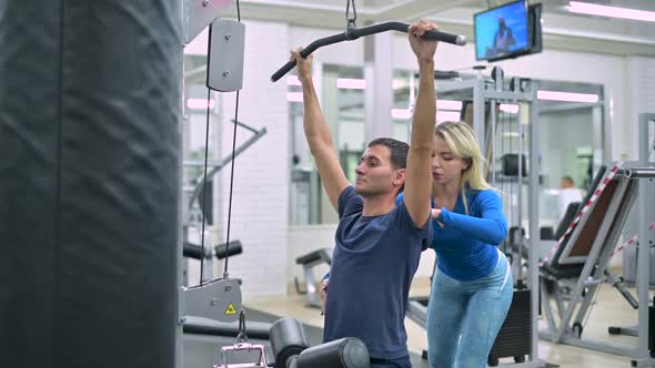 trainer helps the client to control the correctness of the exercise in the gym alt