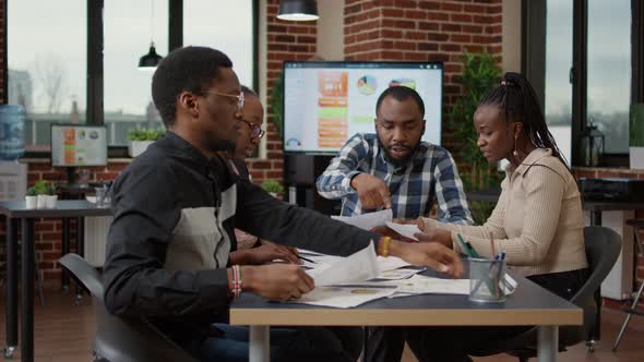 Team of African American Colleagues Analyzing Papers with Charts alt
