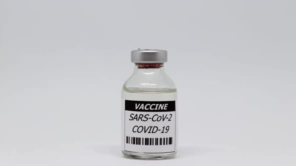 Single Vial Bottle Of Coronavirus Vaccine In White Background - dolly out, studio shot alt