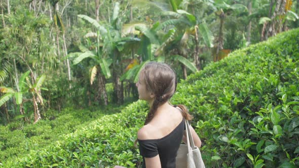 Young Woman in Black T-shirt Walks Along Large Plantation alt