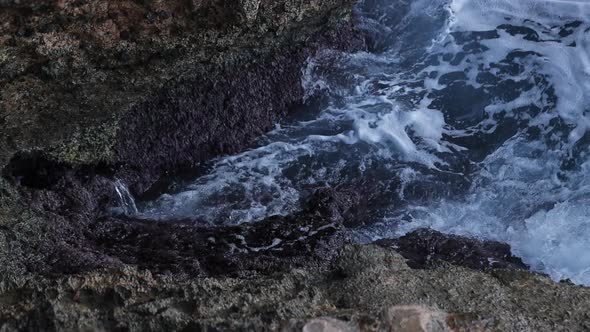 Waves crashing against sea cliff. Detail shot in slow motion of the foam alt